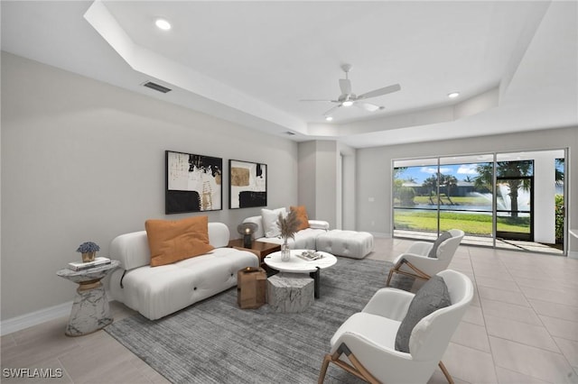 tiled living room featuring a tray ceiling and ceiling fan