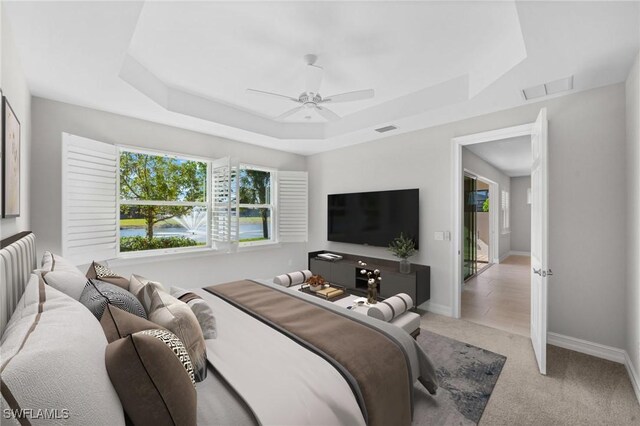 carpeted bedroom with ceiling fan and a tray ceiling