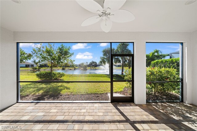 unfurnished sunroom with ceiling fan and a water view