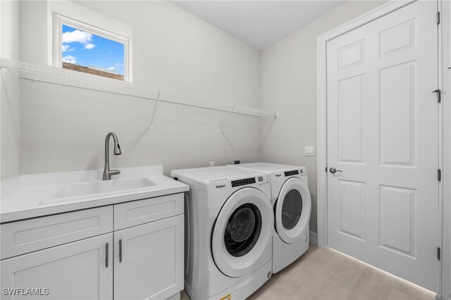 clothes washing area featuring cabinets, washing machine and dryer, and sink