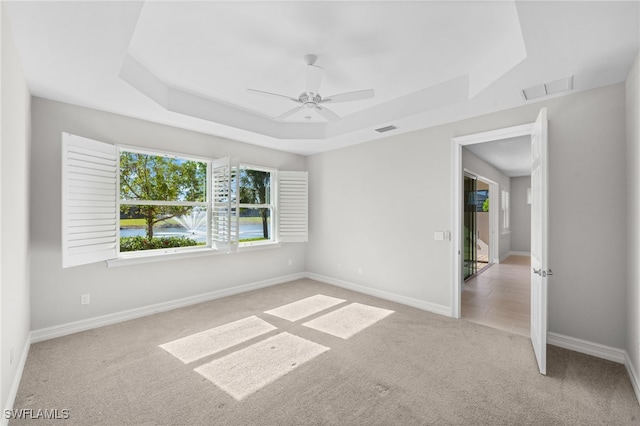 carpeted empty room featuring a tray ceiling and ceiling fan