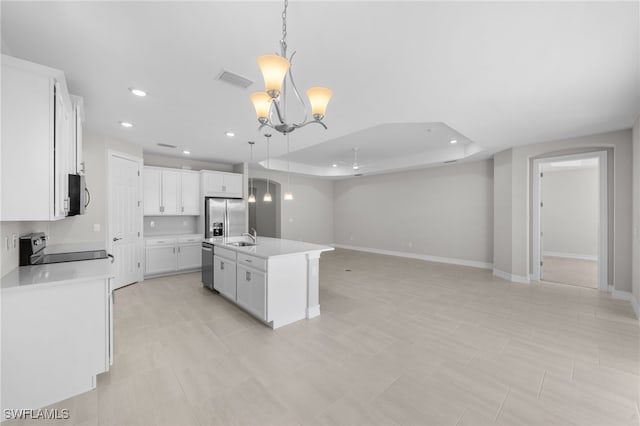 kitchen featuring a tray ceiling, an island with sink, pendant lighting, and appliances with stainless steel finishes