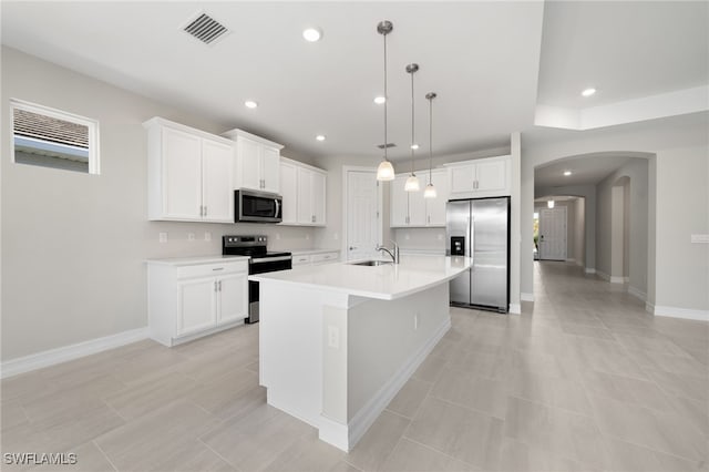 kitchen featuring white cabinetry, a center island with sink, decorative light fixtures, and appliances with stainless steel finishes