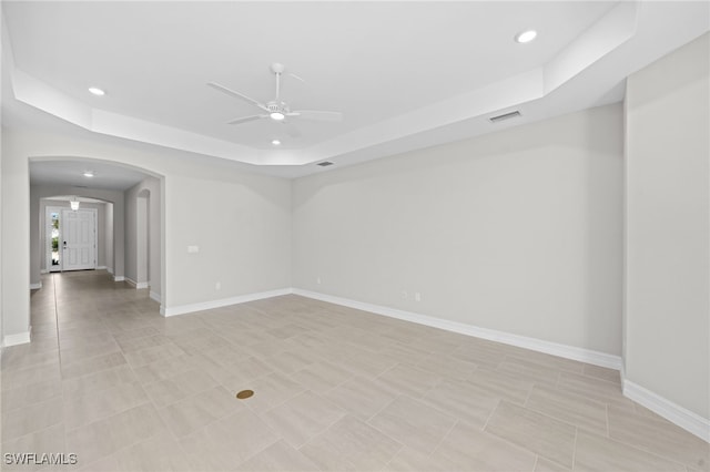 unfurnished room featuring ceiling fan, light tile patterned floors, and a tray ceiling