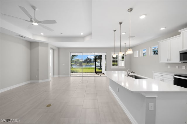 kitchen with ceiling fan, a kitchen island with sink, sink, white cabinets, and hanging light fixtures