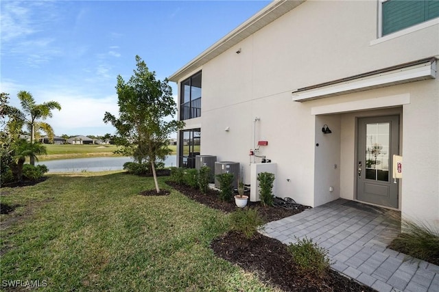 view of property exterior with a yard, a water view, and central AC unit