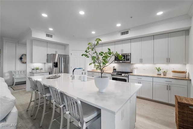 kitchen with backsplash, a center island with sink, a kitchen bar, and stainless steel appliances