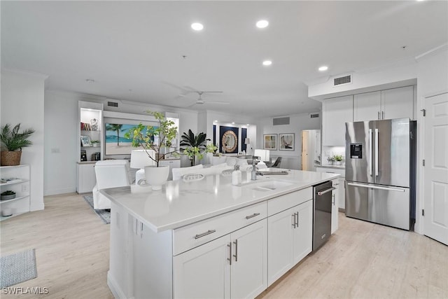 kitchen featuring stainless steel appliances, ceiling fan, sink, a center island with sink, and white cabinetry