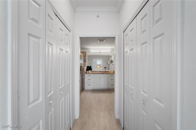 hall with light hardwood / wood-style floors, ornamental molding, and sink