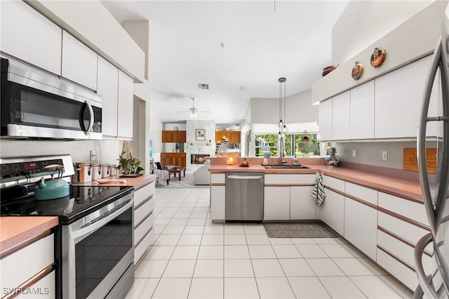 kitchen with appliances with stainless steel finishes, ceiling fan, white cabinets, hanging light fixtures, and light tile patterned flooring