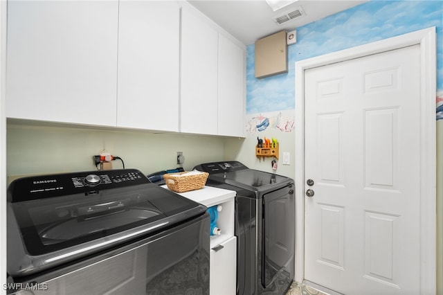 clothes washing area featuring washer and dryer and cabinets