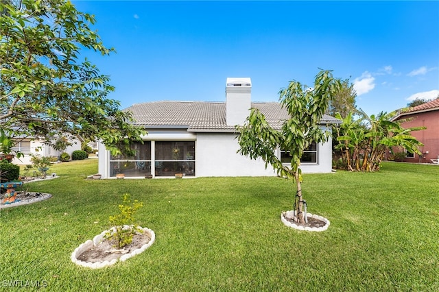 rear view of property with a lawn and a sunroom