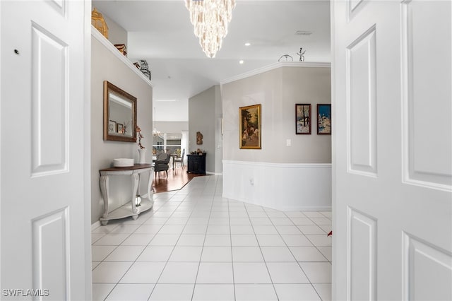 corridor with an inviting chandelier, ornamental molding, and light tile patterned flooring