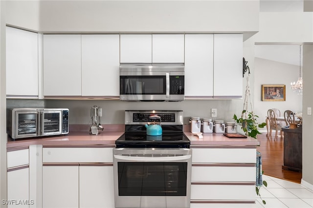 kitchen with appliances with stainless steel finishes, an inviting chandelier, decorative light fixtures, and white cabinetry