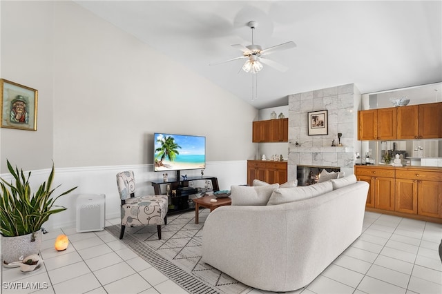 living room with a tile fireplace, ceiling fan, light tile patterned flooring, and high vaulted ceiling