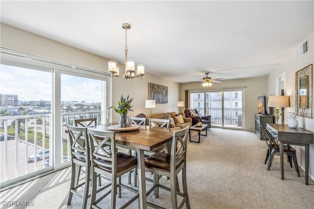 carpeted dining room featuring ceiling fan with notable chandelier