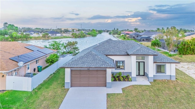 view of front of house with a lawn, a garage, and a water view