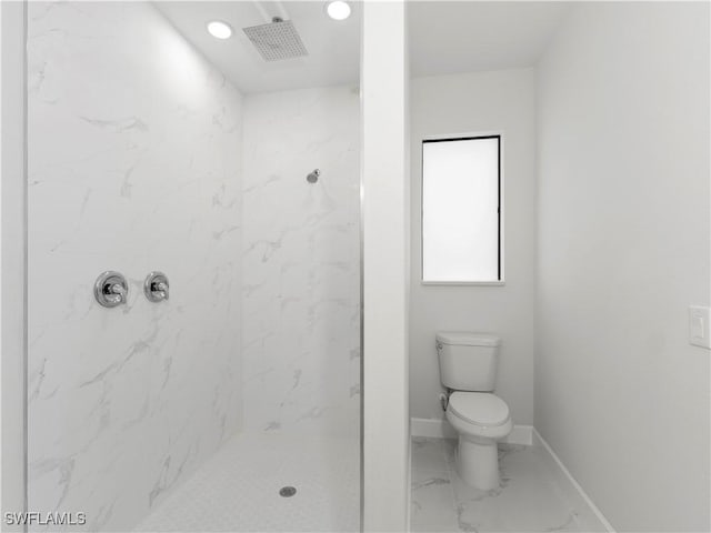 bathroom with a tile shower and toilet