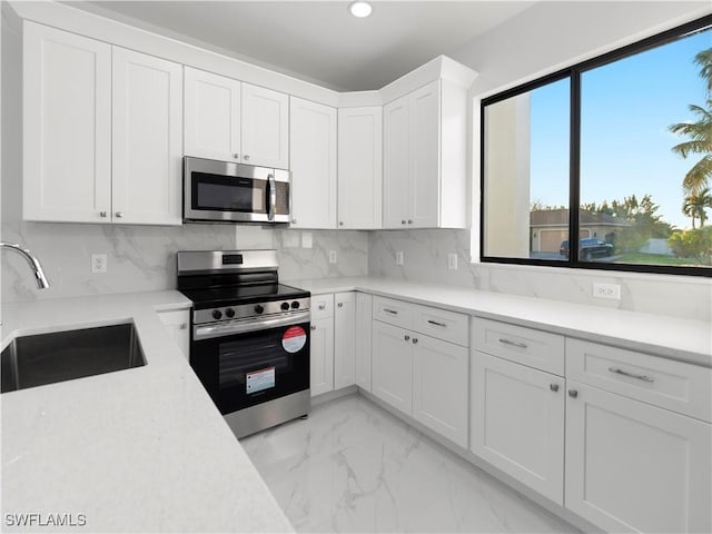 kitchen with decorative backsplash, appliances with stainless steel finishes, white cabinetry, and sink