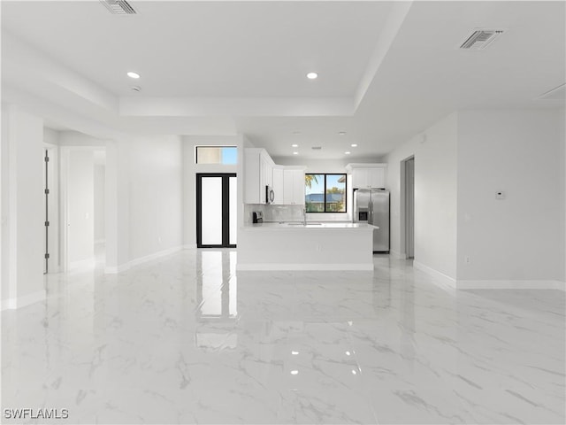 unfurnished living room featuring a raised ceiling and sink