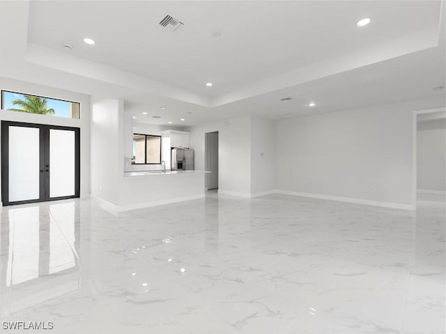 spare room featuring a raised ceiling and french doors