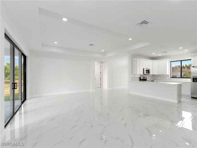 unfurnished living room featuring a tray ceiling