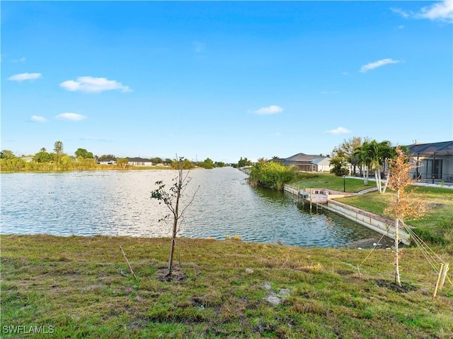 view of dock featuring a lawn and a water view