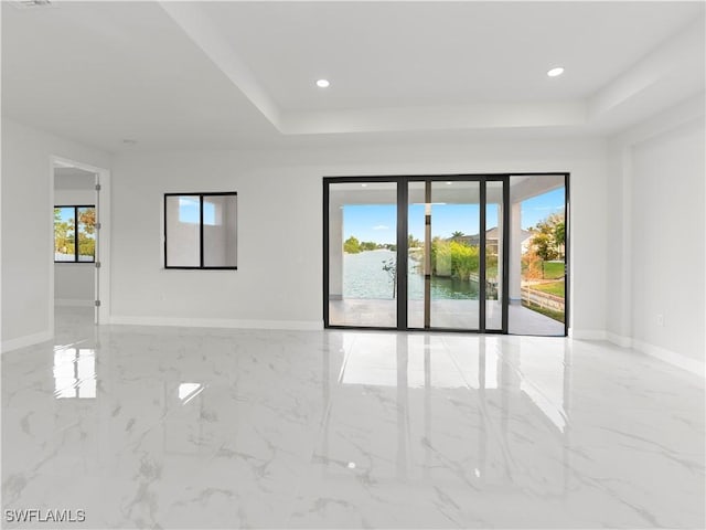 spare room featuring a water view and a raised ceiling