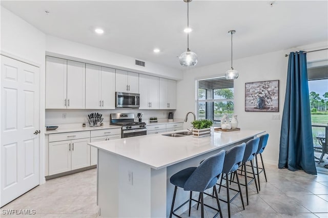 kitchen with a center island with sink, sink, white cabinetry, and stainless steel appliances