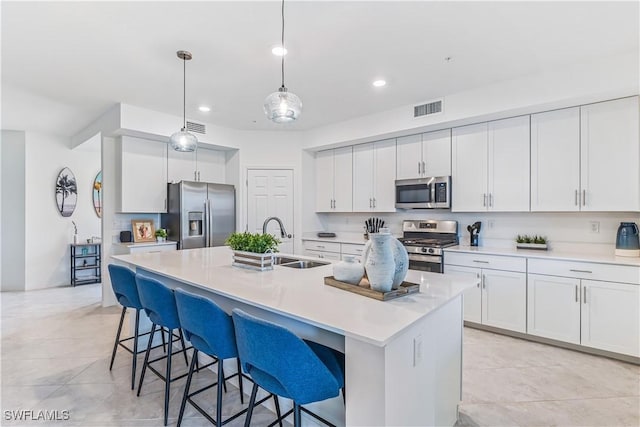 kitchen with appliances with stainless steel finishes, an island with sink, white cabinetry, and sink