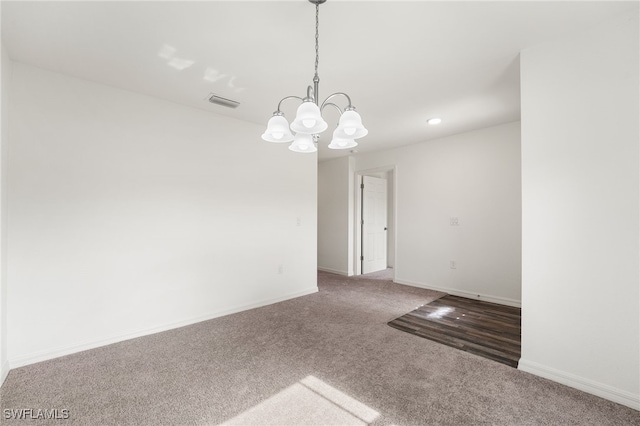 carpeted empty room with a notable chandelier