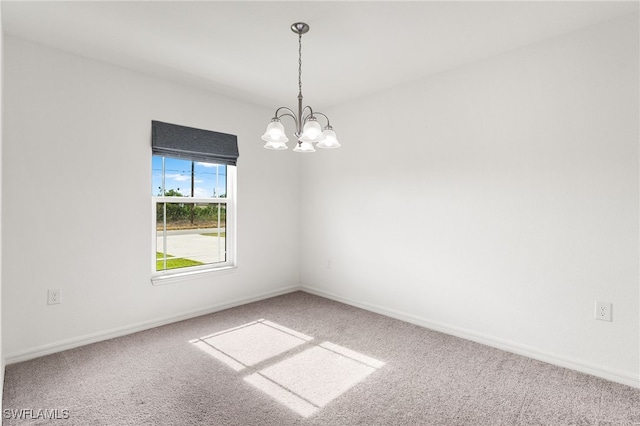 spare room with carpet and an inviting chandelier