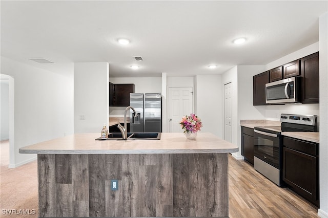 kitchen featuring sink, dark brown cabinetry, stainless steel appliances, and an island with sink