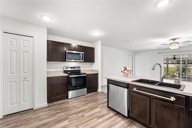 kitchen featuring appliances with stainless steel finishes, sink, ceiling fan, light hardwood / wood-style flooring, and dark brown cabinets