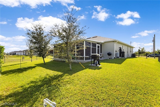 exterior space with a sunroom, cooling unit, and a lawn