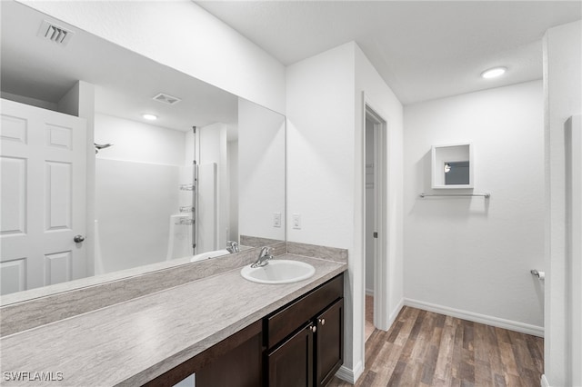 bathroom with walk in shower, vanity, and wood-type flooring