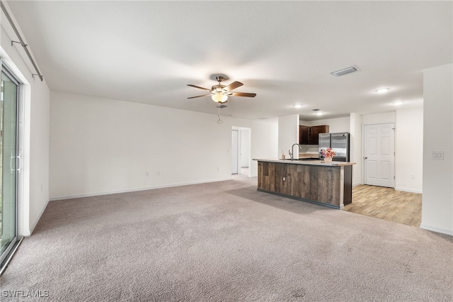 unfurnished living room with light carpet and ceiling fan