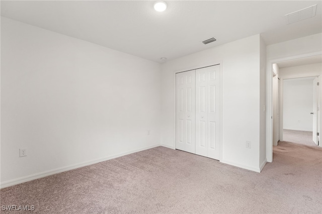 unfurnished bedroom featuring light carpet and a closet