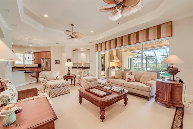 living room featuring ceiling fan, crown molding, and a tray ceiling