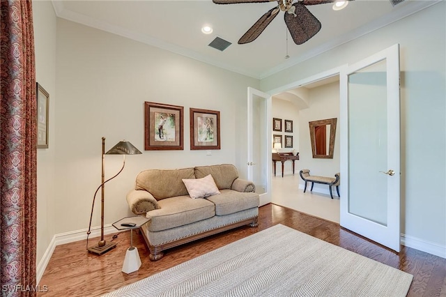 living room with hardwood / wood-style flooring, ceiling fan, and crown molding