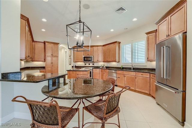 kitchen featuring a center island, hanging light fixtures, dark stone countertops, a kitchen bar, and stainless steel appliances