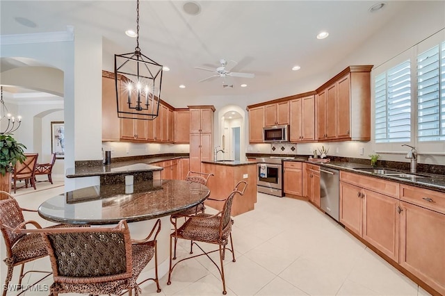 kitchen with appliances with stainless steel finishes, ornamental molding, sink, decorative light fixtures, and a center island