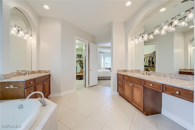 bathroom with tile patterned flooring, vanity, and tiled tub