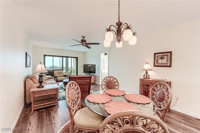 dining area with ceiling fan with notable chandelier and wood-type flooring