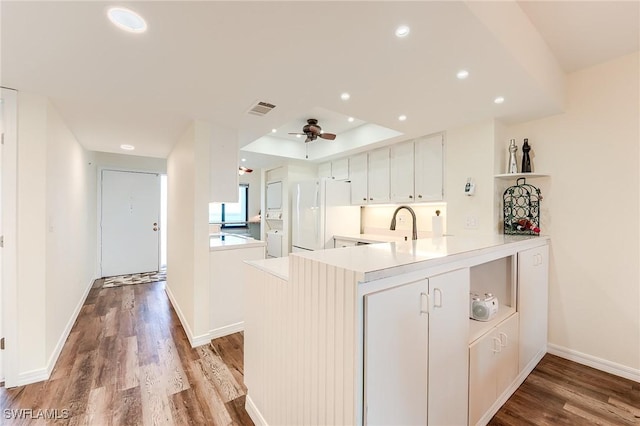 kitchen featuring white cabinetry, white refrigerator, hardwood / wood-style flooring, ceiling fan, and kitchen peninsula