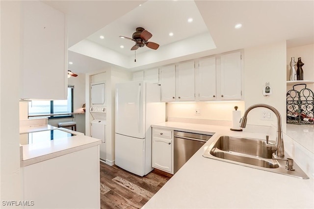 kitchen with sink, white cabinets, white refrigerator, stainless steel dishwasher, and a raised ceiling