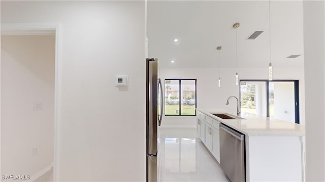 kitchen with pendant lighting, white cabinets, a center island with sink, sink, and appliances with stainless steel finishes