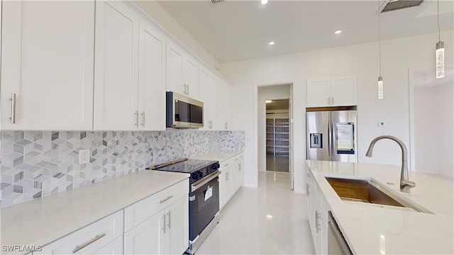 kitchen featuring pendant lighting, sink, appliances with stainless steel finishes, light stone countertops, and white cabinets