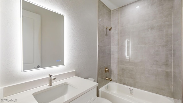 full bathroom with tiled shower / bath, vanity, and toilet