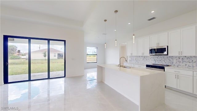 kitchen with sink, decorative light fixtures, appliances with stainless steel finishes, a kitchen island with sink, and white cabinets